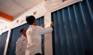 Petugas dari Pemerintah Kabupaten Ogan Komering Ilir sedang melakukan pemasangan stiker pada kios pedagang yang menunggak retribusi di Pasar Rakyat Kayuagung, pada hari Rabu, tanggal 3 Desember 2025. (foto : Humas Pemkab OKI)